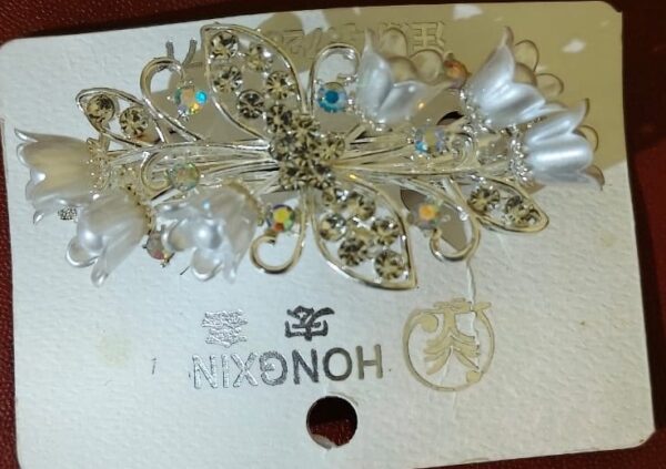 Silver floral hair clip with crystals and pearl petals for women.